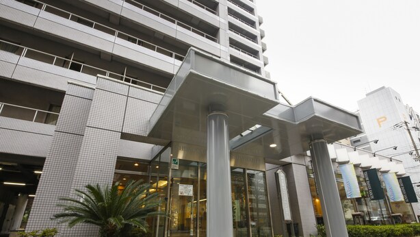 Un edificio moderno con entrada de vidrio, pilares grandes y un cartel que indica que es un hotel.