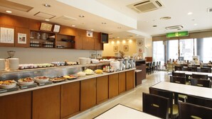 Un área para desayuno tipo buffet con diversas opciones de comida, una barra de bebidas y un espacio de estar con mesas y sillas.