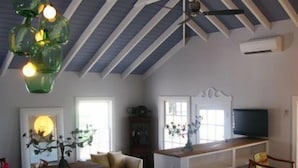 A room with a sloped ceiling, a wooden desk, a sofa, and a television.
