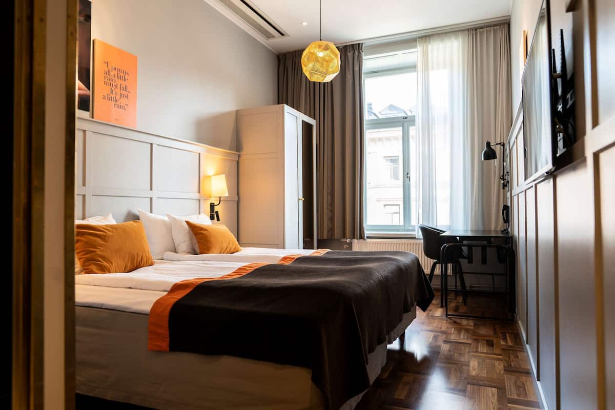 Una habitación de hotel con cama, escritorio y ventana con cortinas.