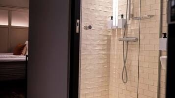 Un baño con cabina de ducha de vidrio, un lavabo blanco y un perchero para toallas.