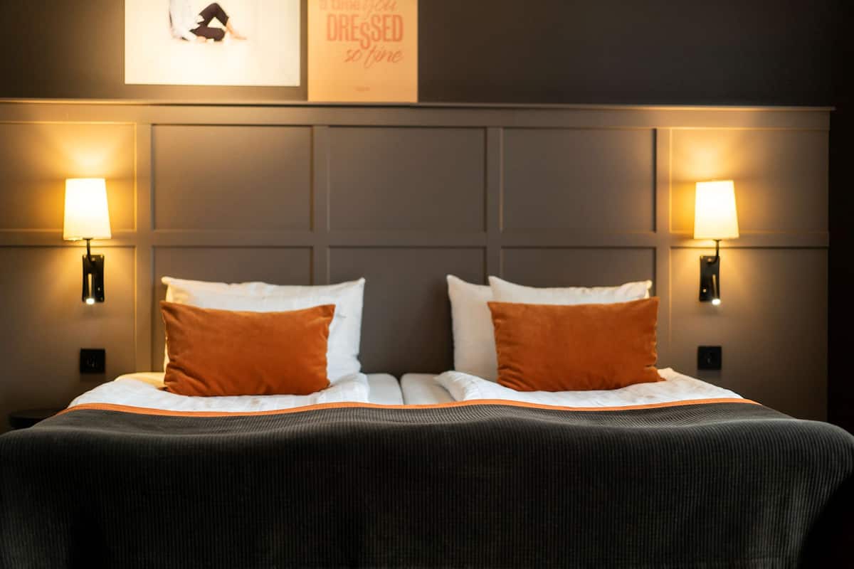 Una habitación de hotel con una cama grande, dos lámparas de noche y una obra de arte en la pared.