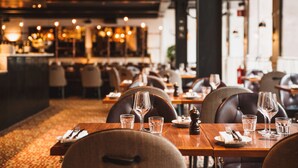 Un restaurante con mesas dispuestas para comer, incluyendo copas de vino y cubiertos.