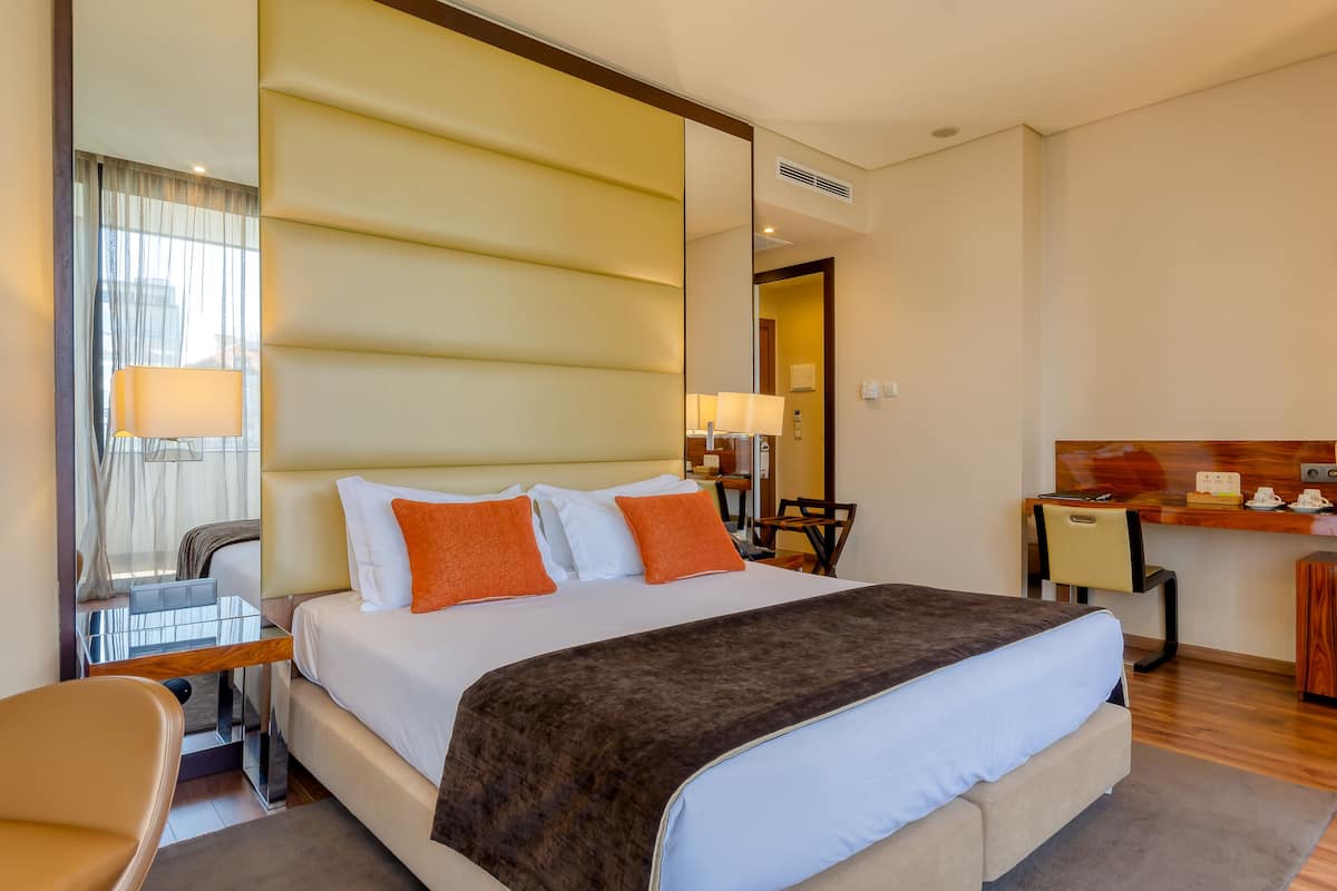 Ein Hotelzimmer mit einem großen Bett, einem Schreibtisch, einem Stuhl und einem Spiegel.
