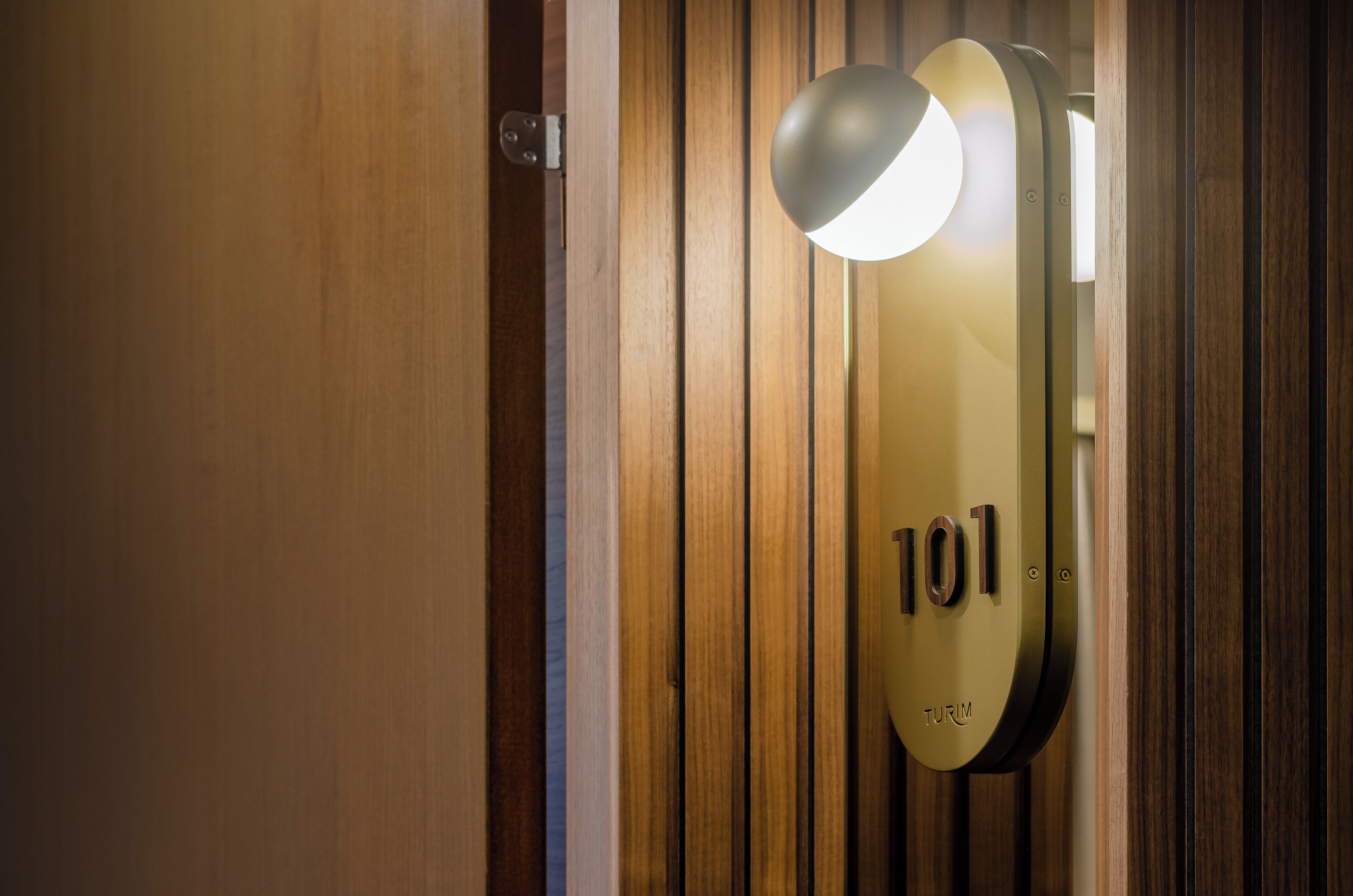 Une porte avec une plaque portant le numéro « 101 » et un luminaire placé au-dessus.