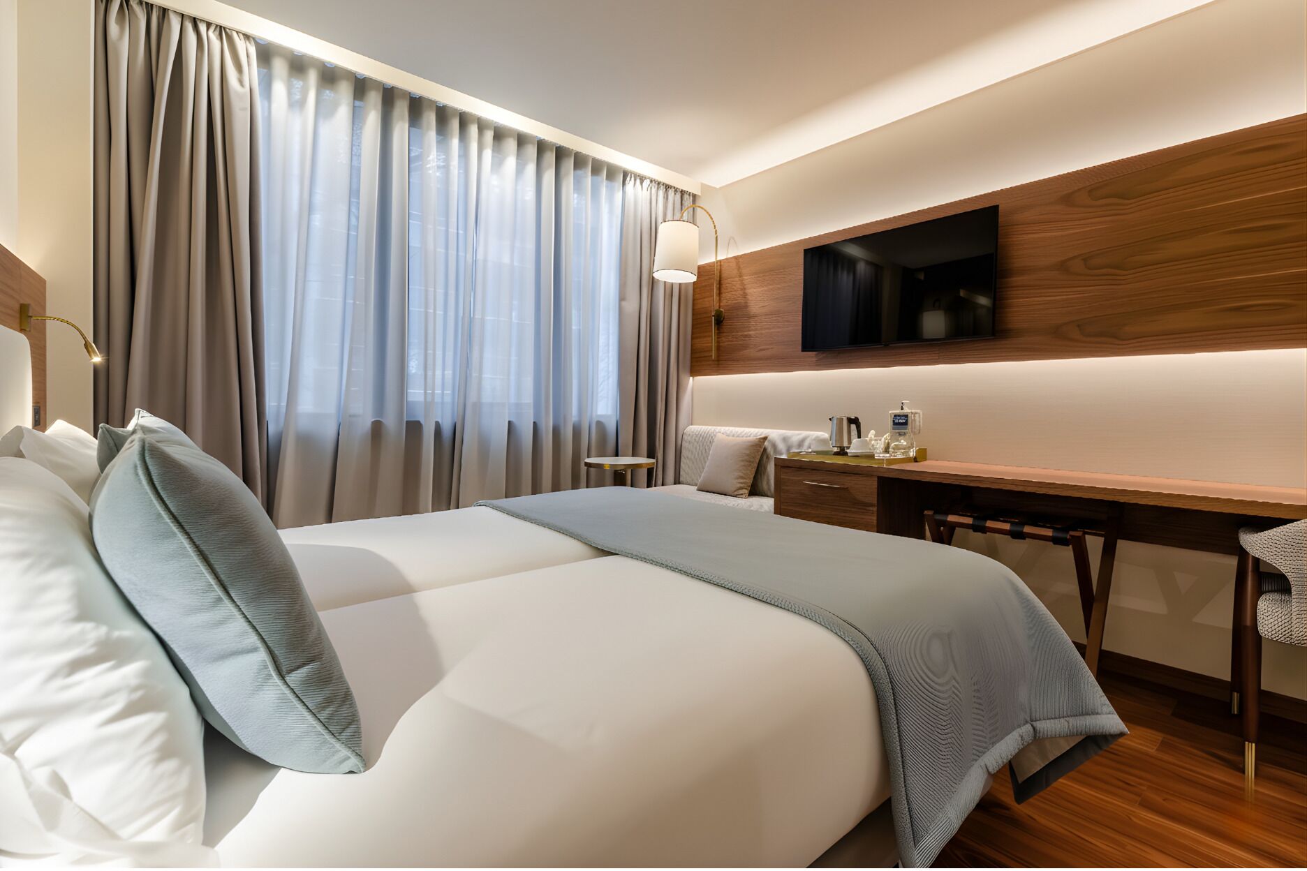 Ein Hotelzimmer mit einem großen Bett, einem Schreibtisch, einem Stuhl, einem Fernseher und einem Fenster mit Vorhängen.