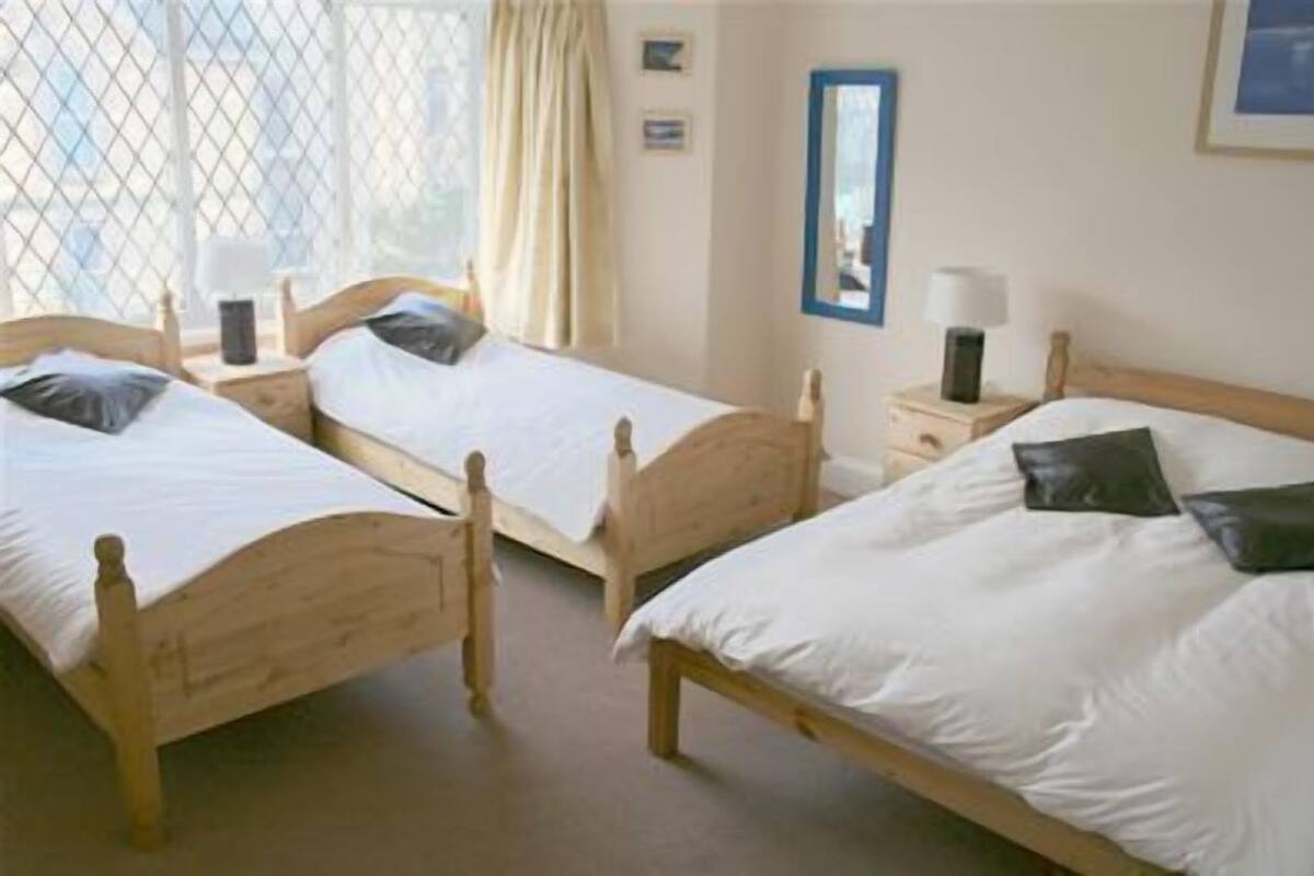A room with two wooden beds, each with white linens and black pillows. There are bedside tables with lamps.
