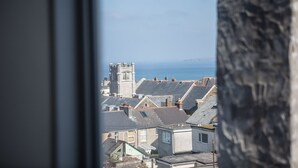 A coastal town with traditional architecture, including a prominent tower and terraced houses with sloped roofs. - St Breca (Newquay)