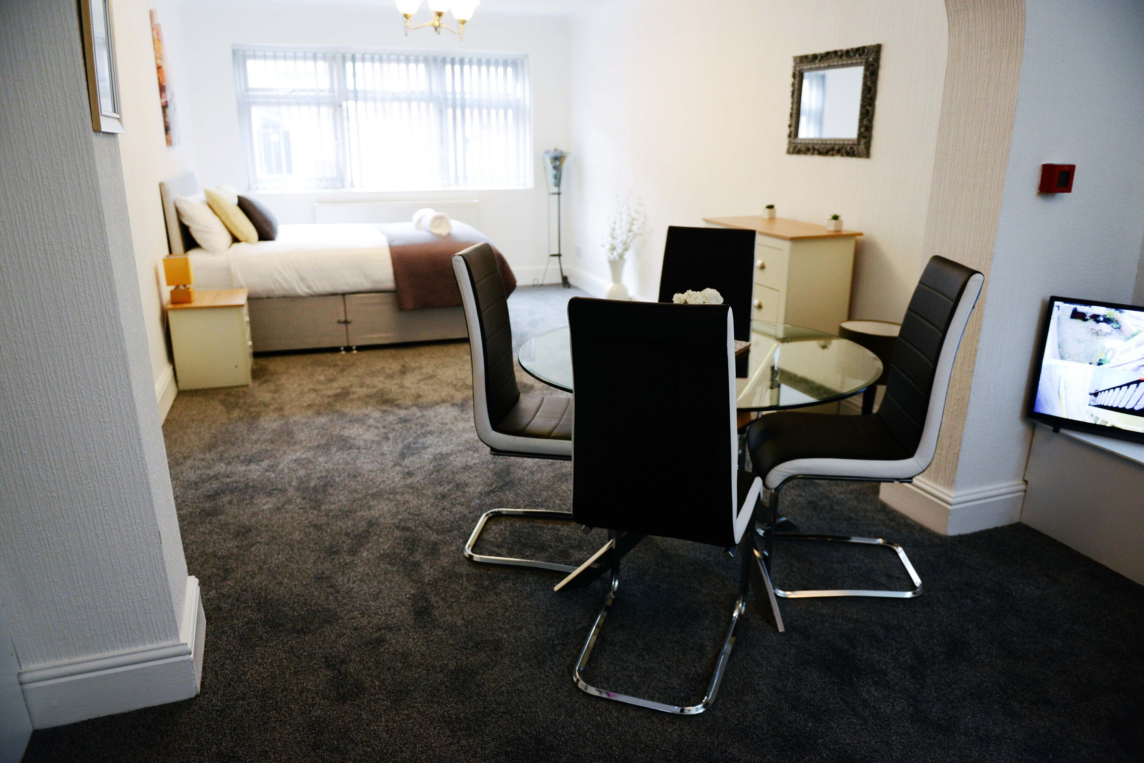 Een hotelkamer met een bed, een bureau met een stoel, een klein tafeltje en een televisie.