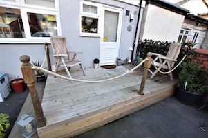 A wooden deck with two wooden chairs and a rope barrier.