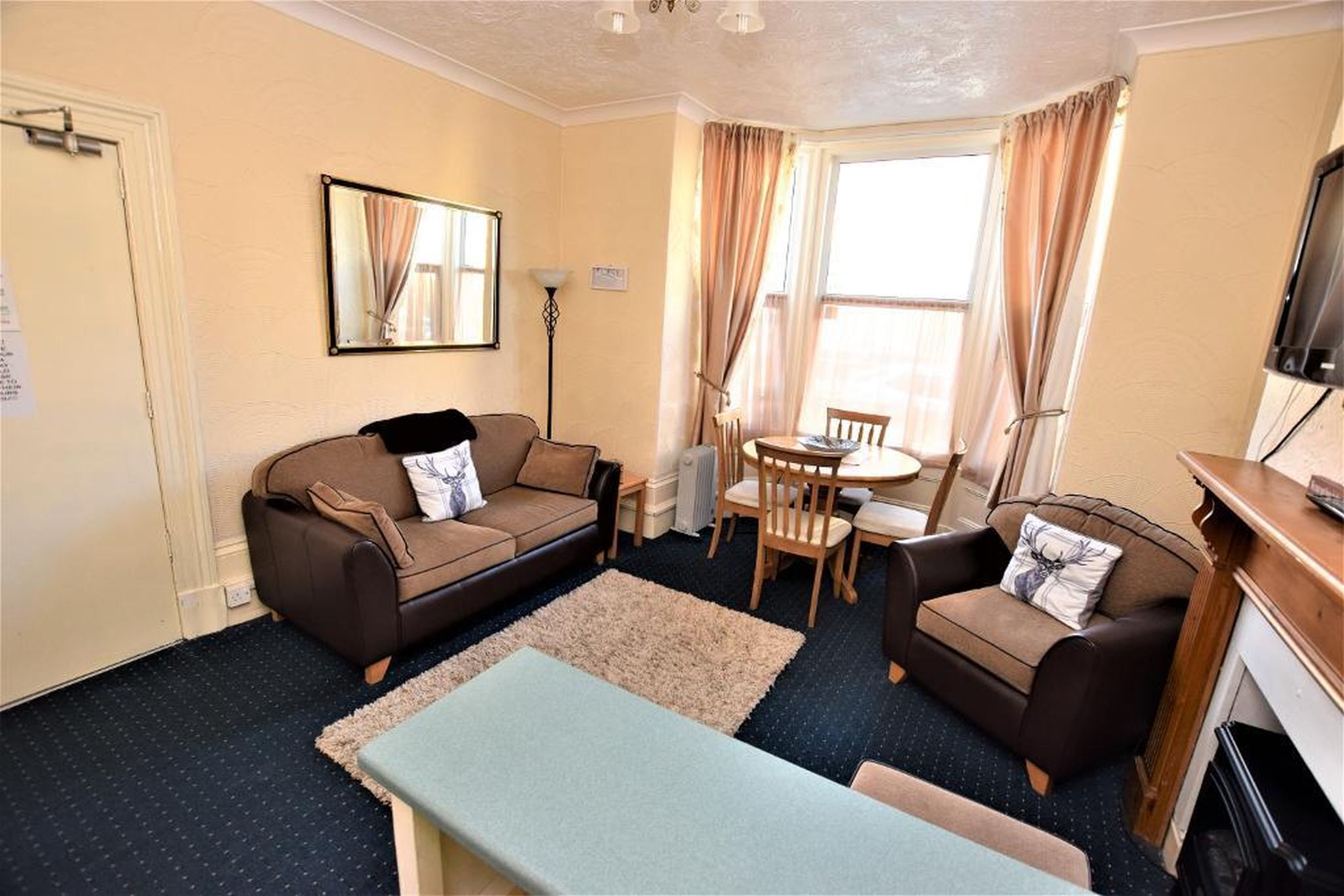A cozy living room with a sofa, armchair, and a small dining table.