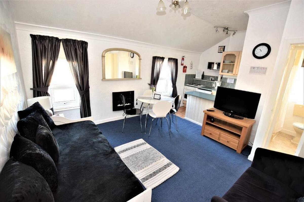 Ein gemütlicher, kleiner Wohnbereich mit Sofa, Essplatz, Fernseher und Küchenzeile.