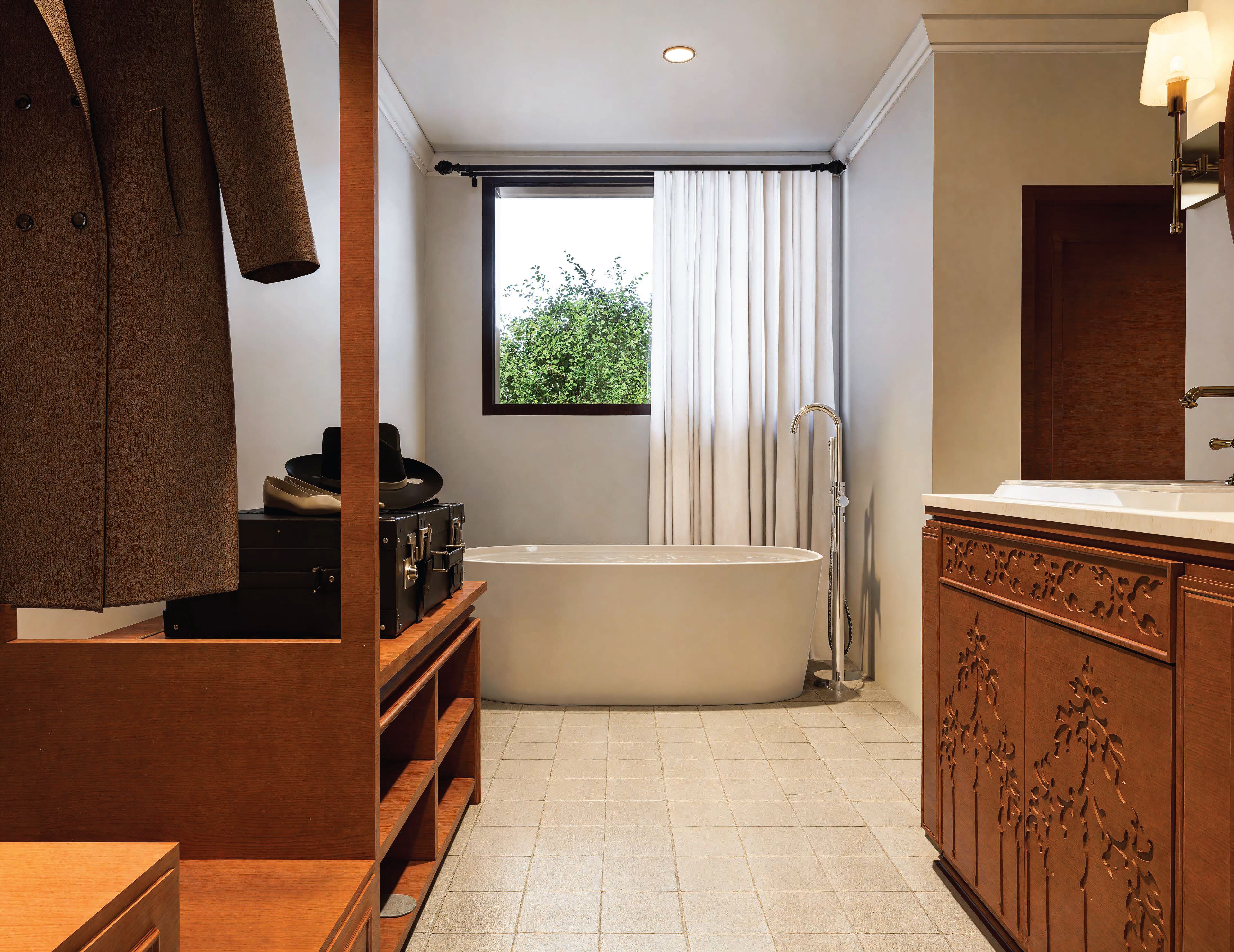 A modern bathroom with a freestanding bathtub, wooden cabinetry, and a large window with curtains.