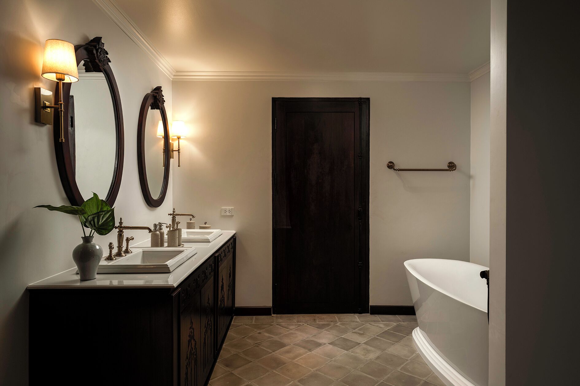 Un bagno con doppio lavabo, uno specchio grande, una porta scura e una vasca freestanding.