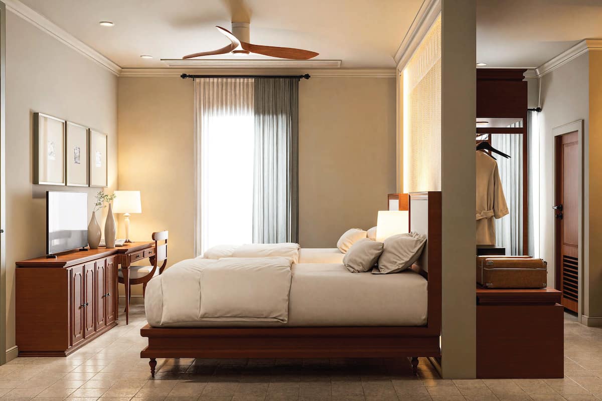 Quarto espaçoso com uma cama grande, uma escrivaninha com abajur, um guarda-roupa e um ventilador de teto.