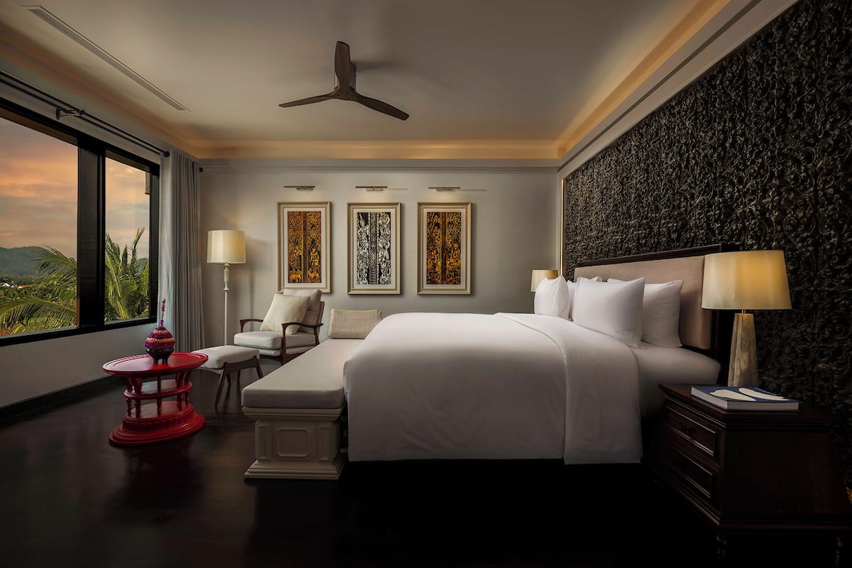Quarto de hotel com uma cama grande, uma escrivaninha, uma cadeira e vista para o exterior.