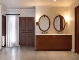 A bathroom with a wooden vanity, two round mirrors, and a double sink.