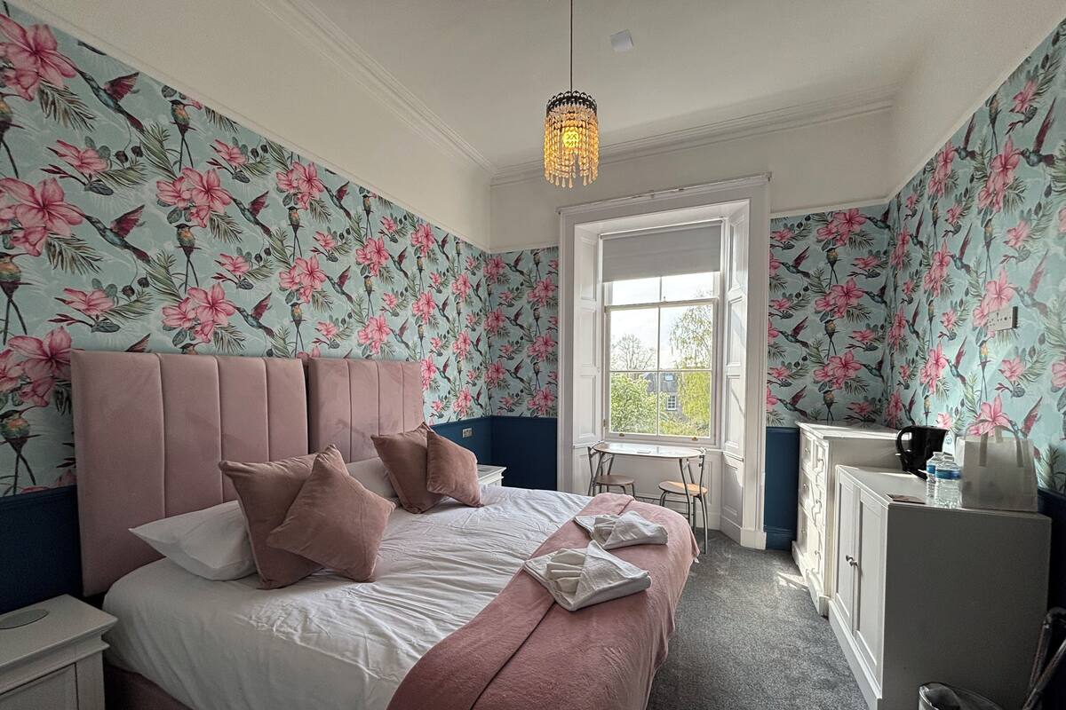 A bedroom with a bed, a dresser, a desk, and a window.