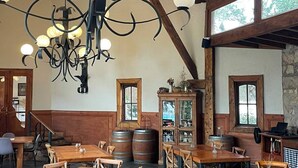 Un interior rústico con vigas de madera, una araña y mesas y sillas de madera.