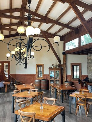 Un interior rústico con vigas de madera, una araña y mesas y sillas de madera.