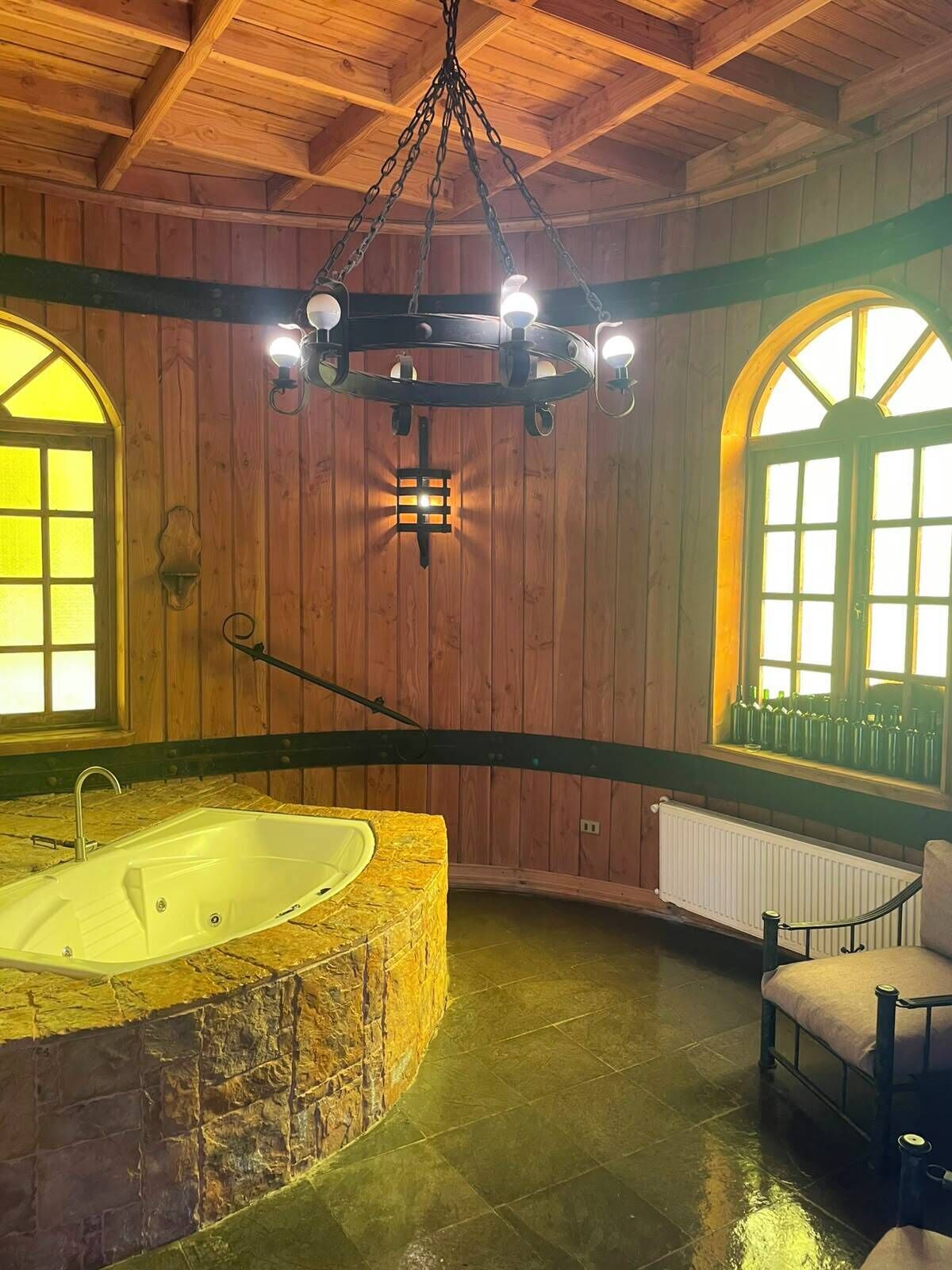 Un interno in legno con una vasca da bagno ampia, un lampadario e finestre ad arco.