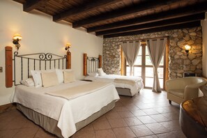 Une chambre avec deux lits, des murs en pierre, un plafond en bois et une cheminée en pierre.