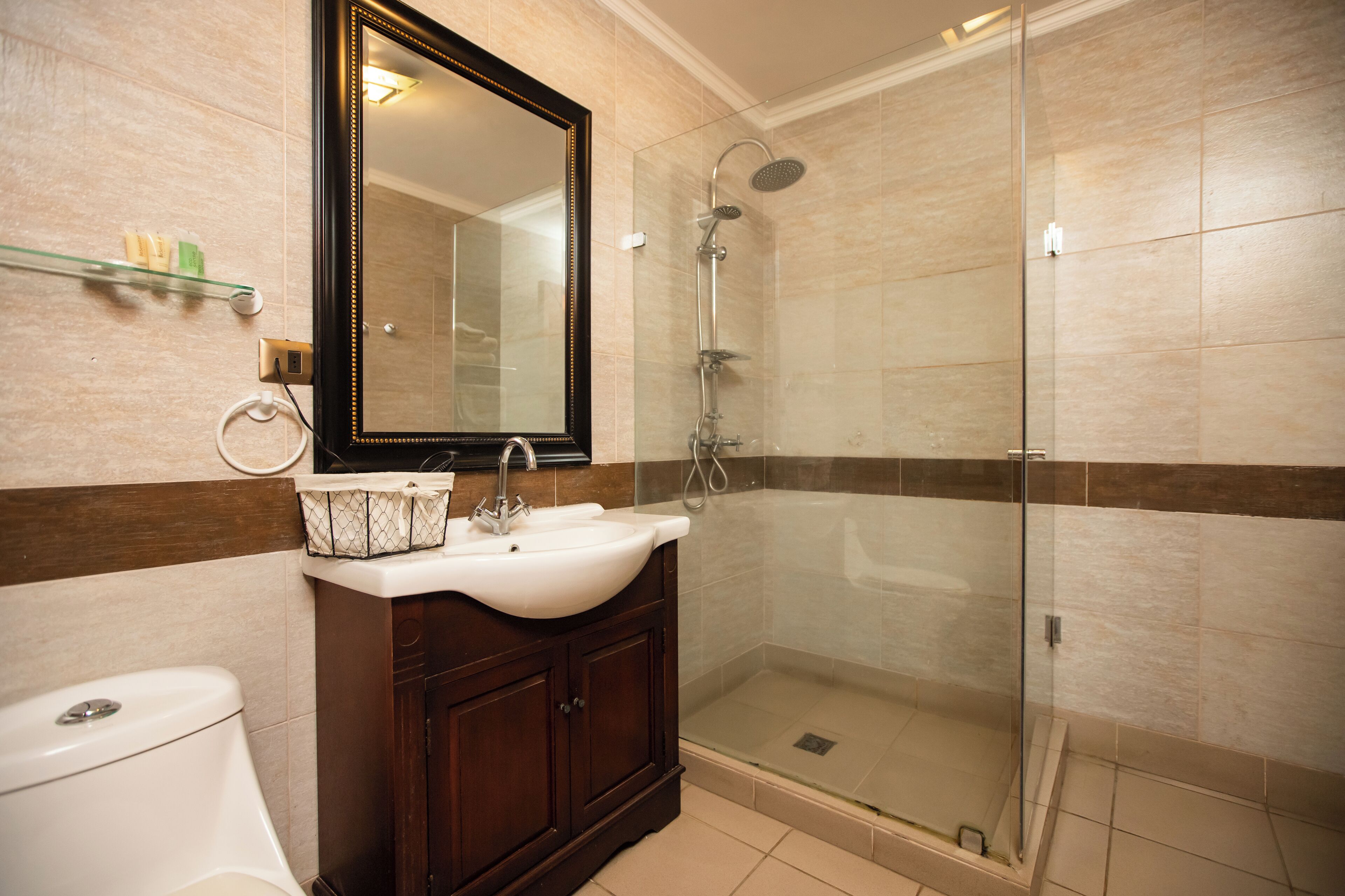A bathroom with a glass-enclosed shower, a sink, and a toilet.