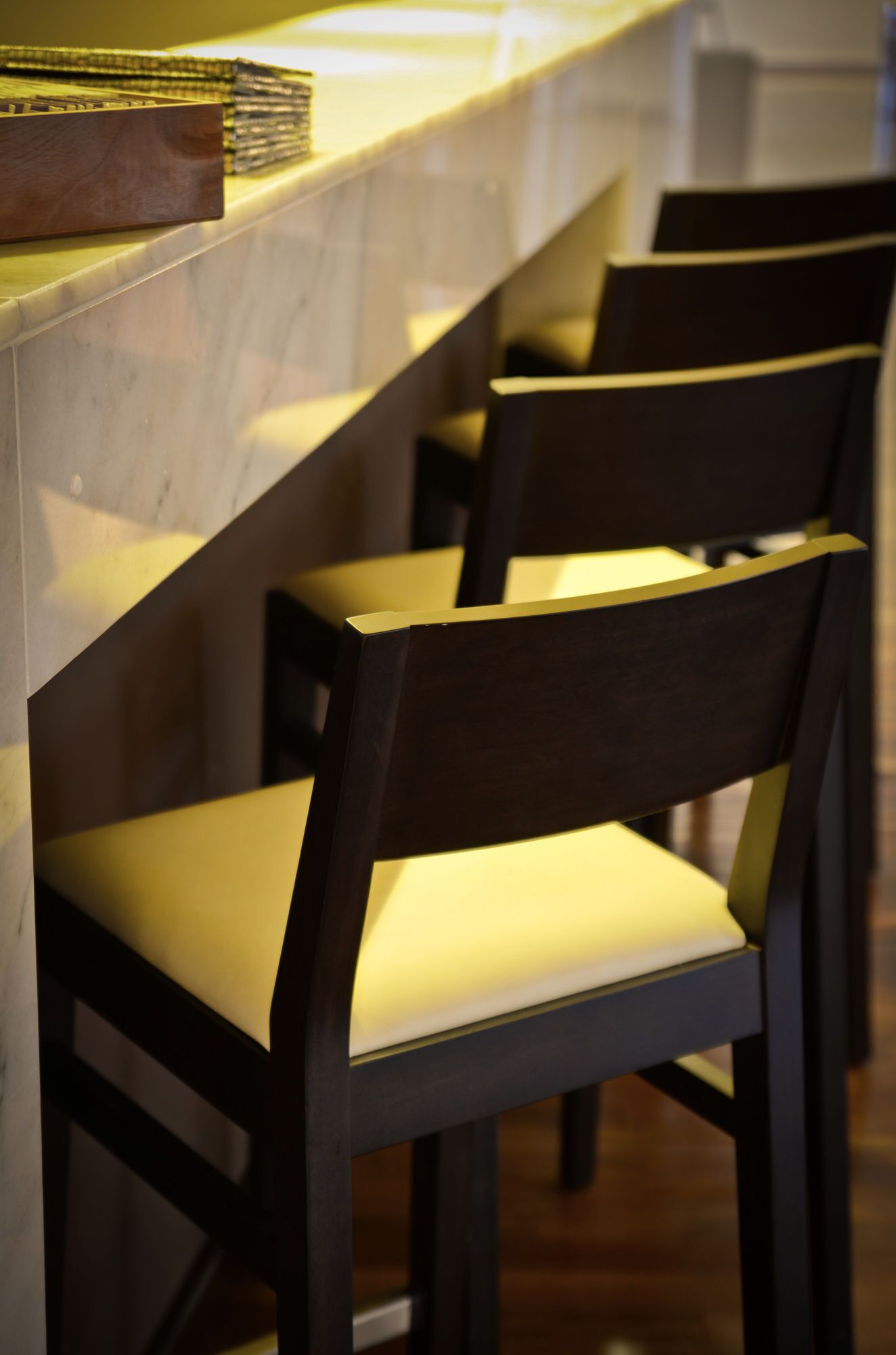 A row of bar stools with cushioned seats and dark wooden backs.