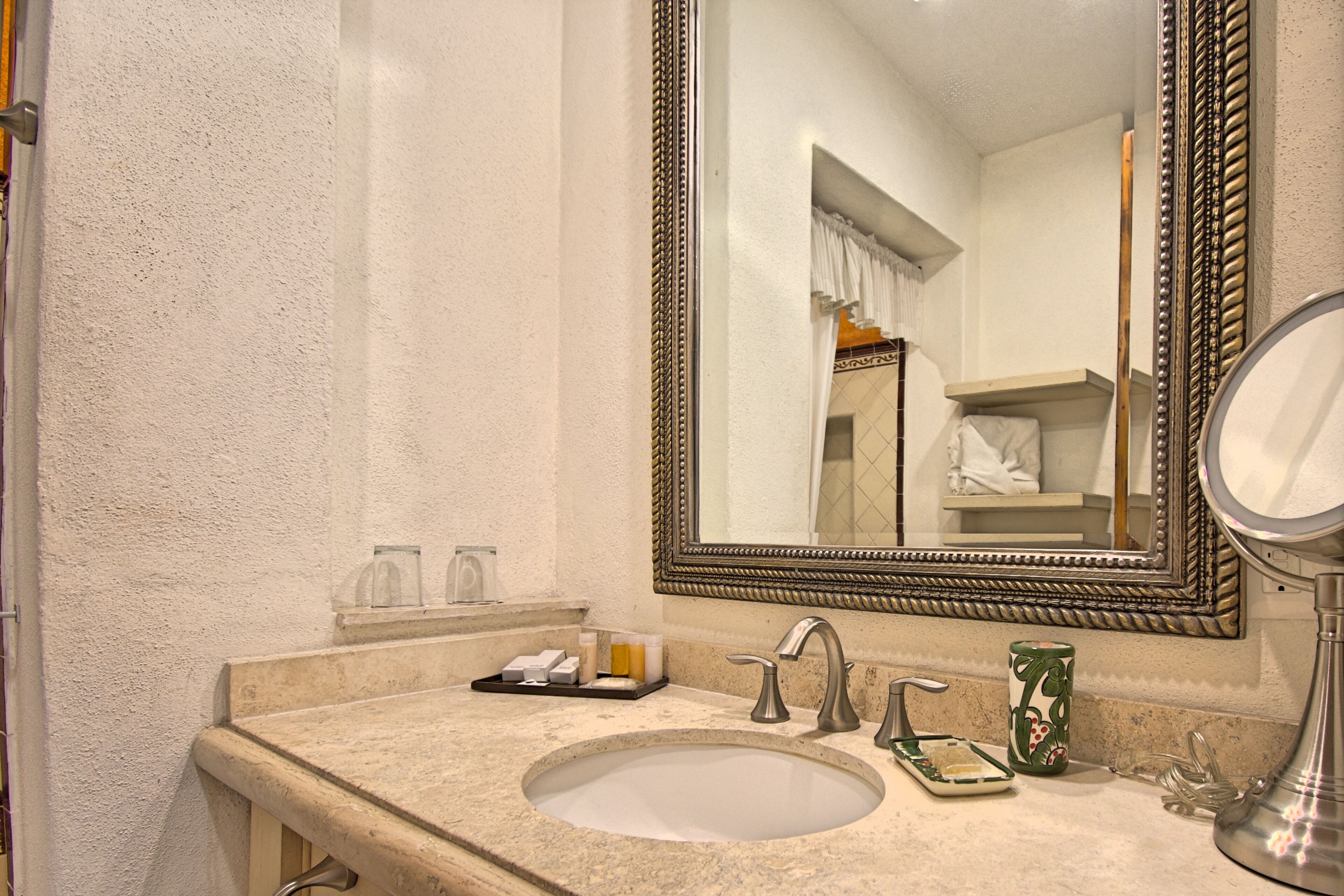 Un baño con un espejo grande, un lavabo y artículos de aseo.