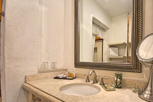Un baño con un espejo grande, un lavabo y artículos de aseo.