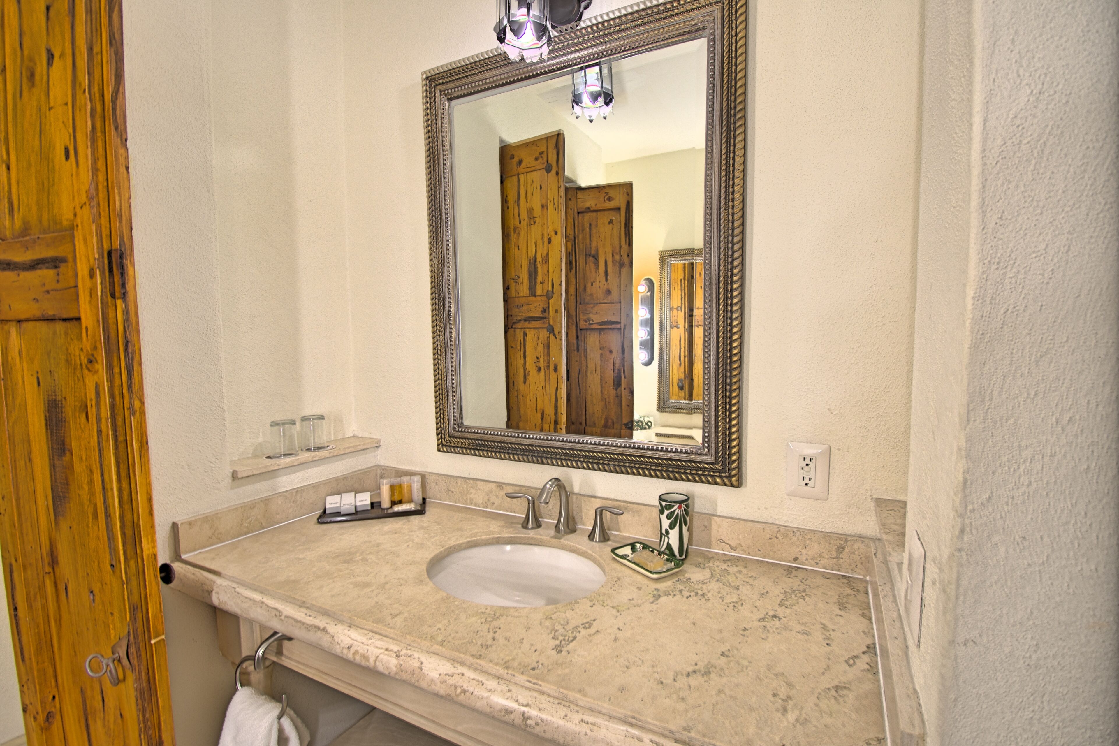 A bathroom with a large mirror, a sink, and a wooden door.
