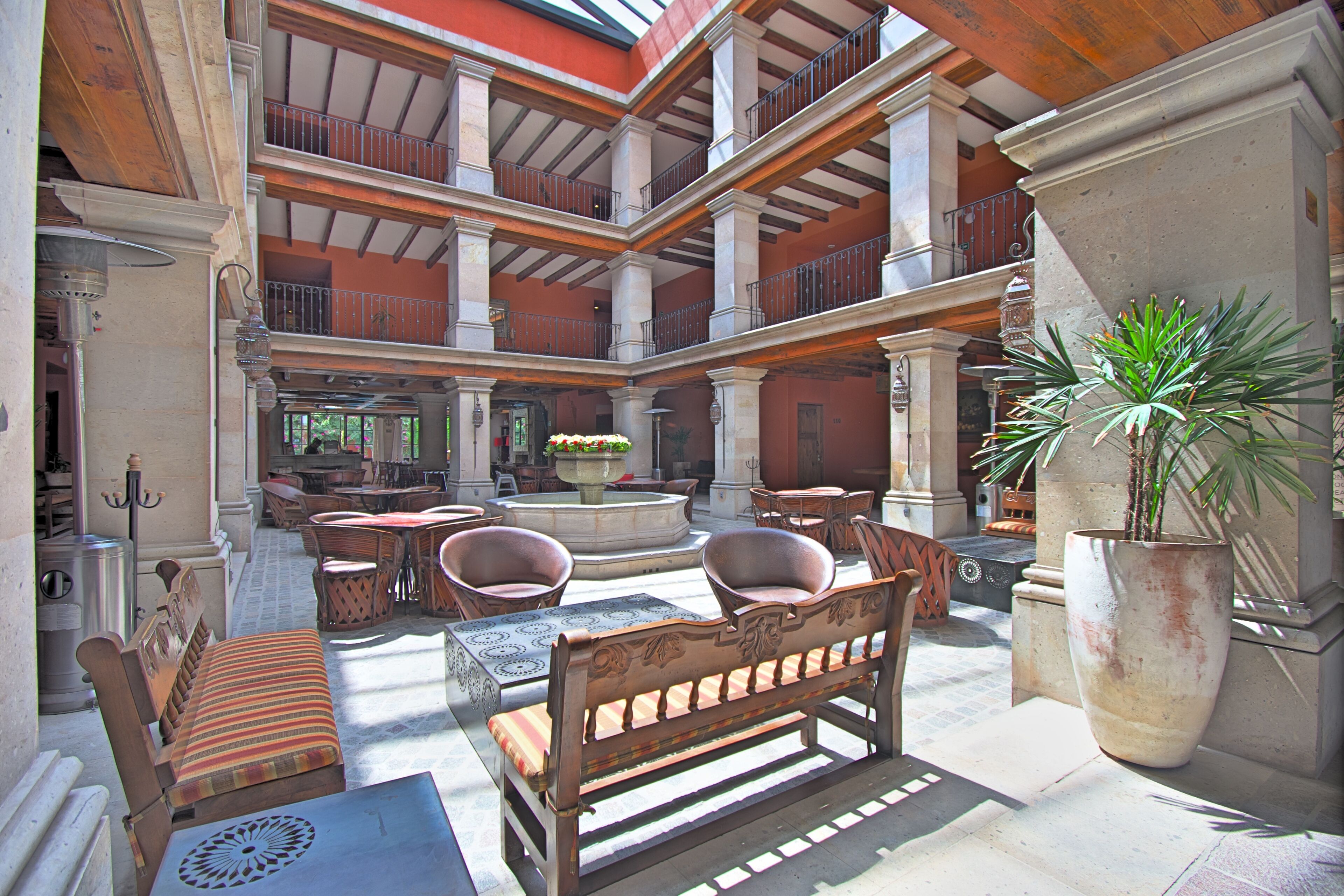 A spacious atrium with a central fountain, multiple seating areas, and a large potted plant.