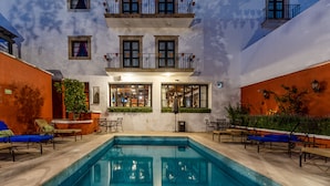 A pool area with lounge chairs, a small pool, and a building with multiple windows and balconies. - Casa Primavera Hotel Boutique & Spa (San Miguel de Allende)