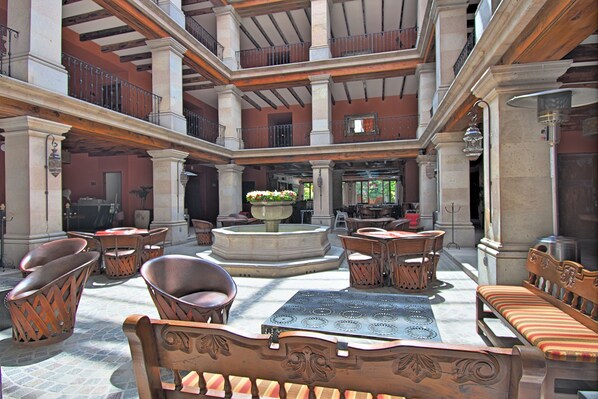 Un patio amplio con varias zonas de estar, una fuente central y vistas de los edificios circundantes.