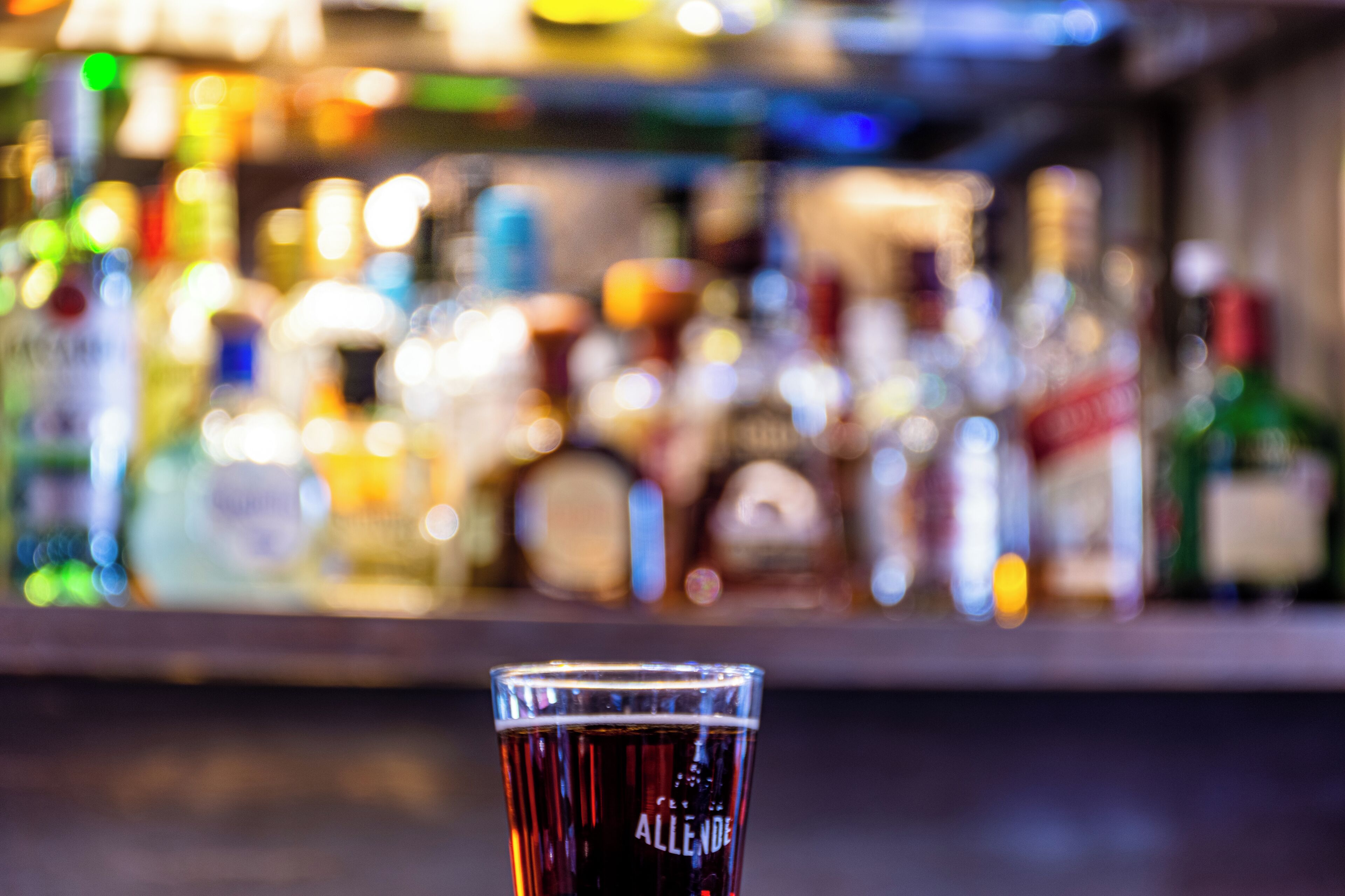 A bar with a glass of dark liquid, possibly beer, in the foreground.