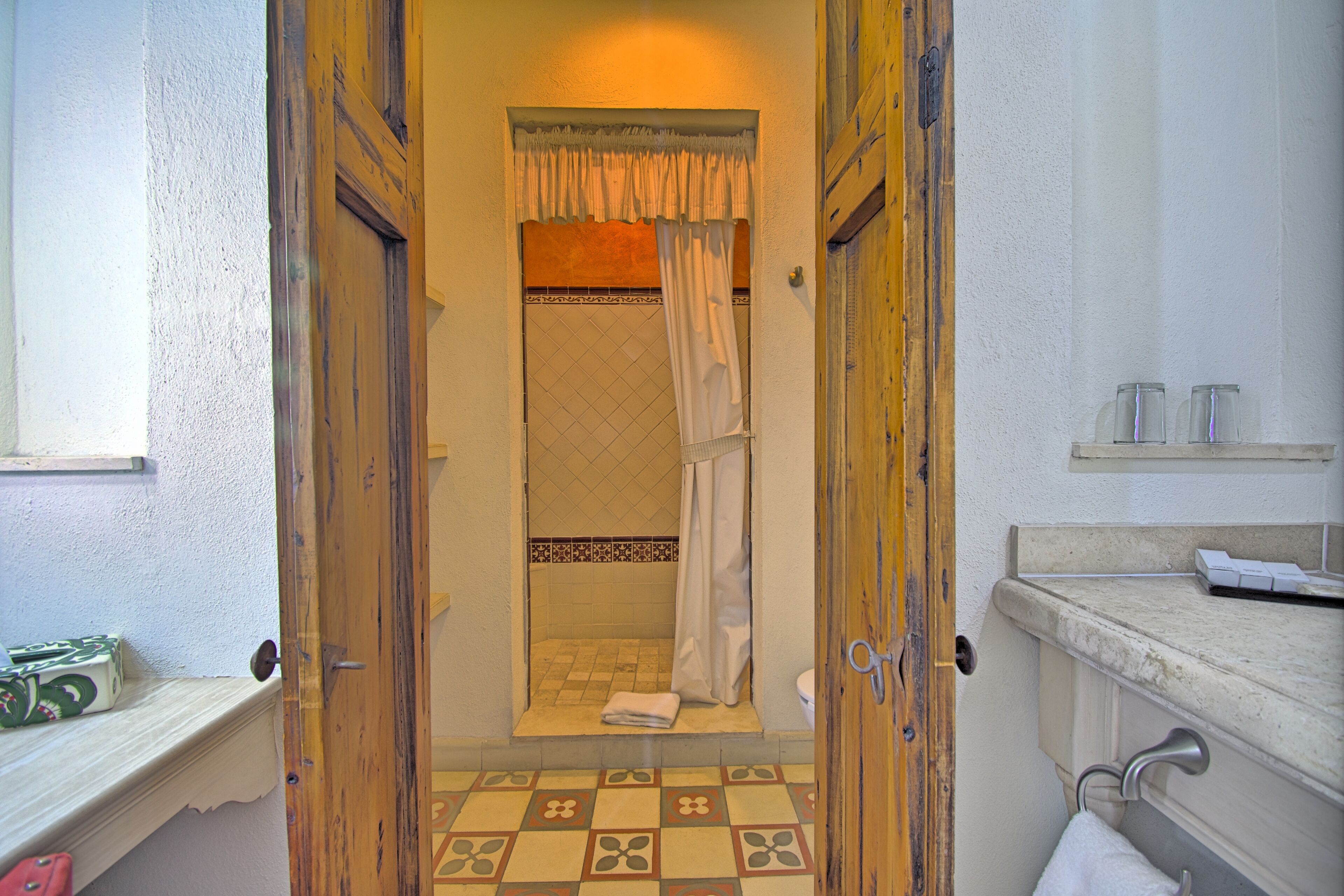 Un baño con piso a cuadros, ducha con cortina y una toalla en el suelo.