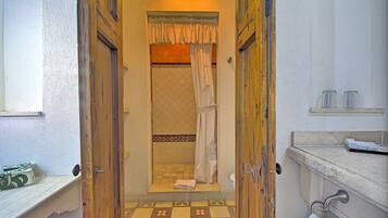 Un baño con piso a cuadros, ducha con cortina y una toalla en el suelo.