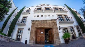 A white building with balconies and a large wooden entrance door. - Casa Primavera Hotel Boutique & Spa (San Miguel de Allende)