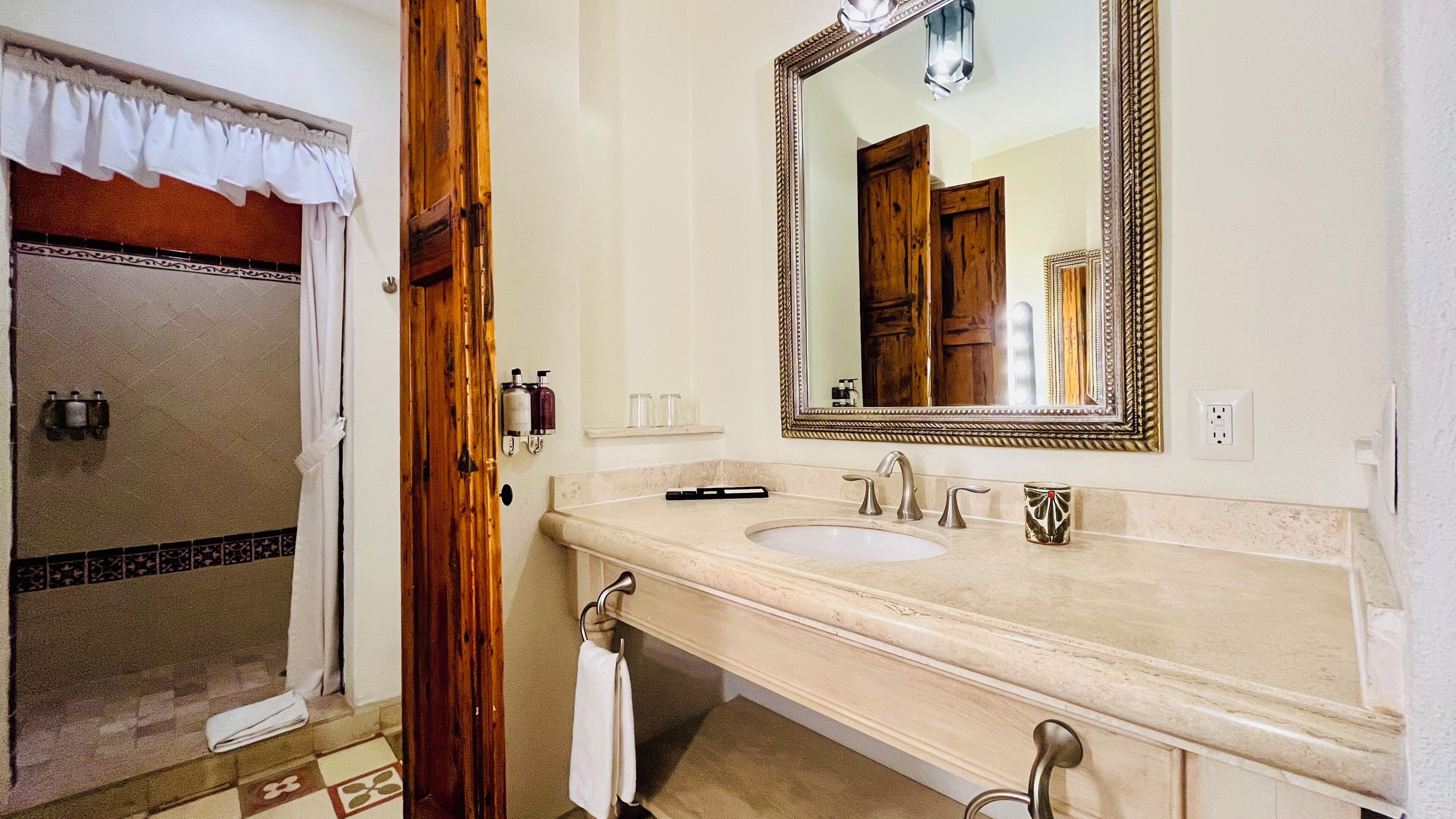 Une salle de bain équipée d’un lavabo, de deux robinets, d’un miroir et d’un espace douche.