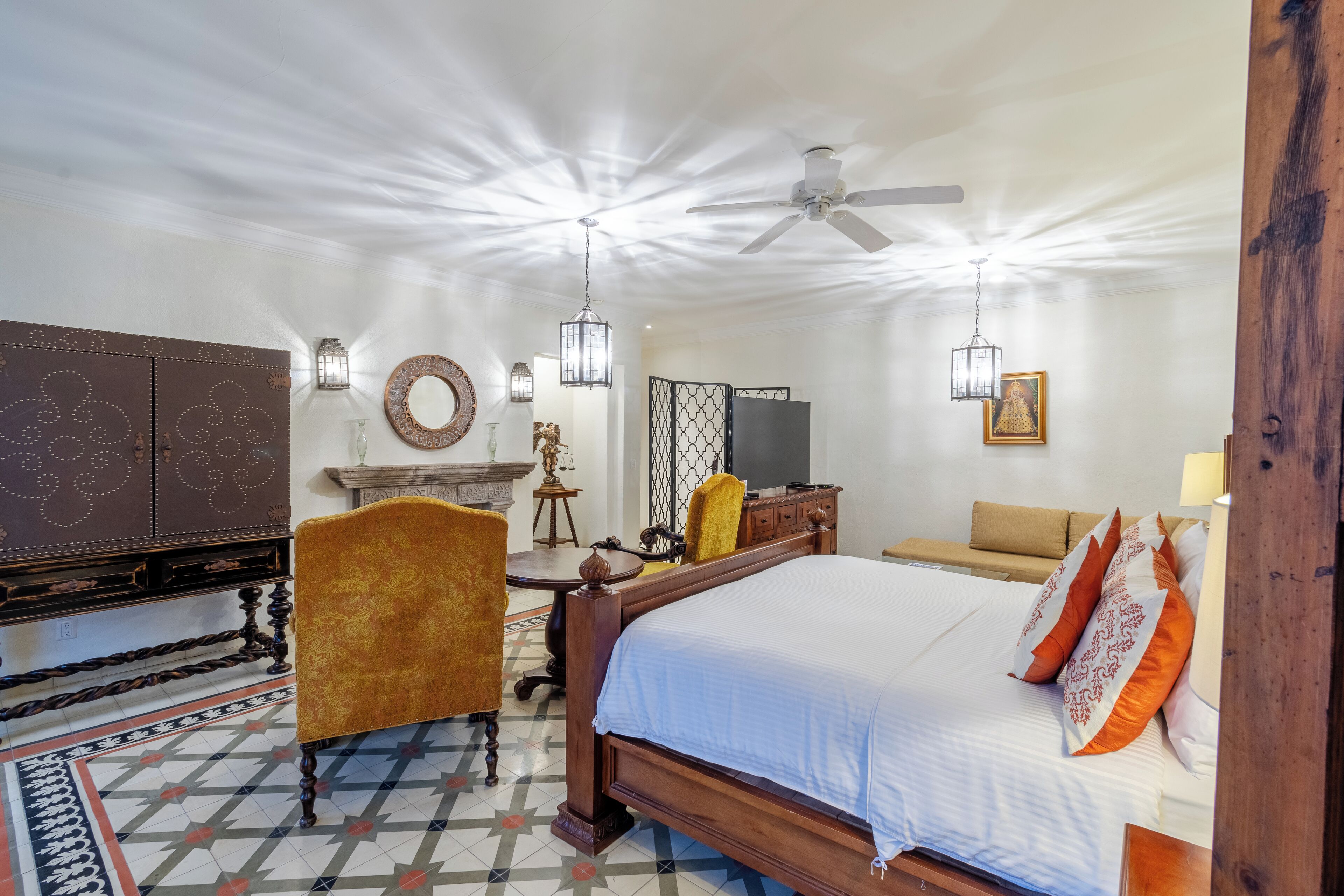 Habitación de hotel con una cama grande, un escritorio de madera, un televisor y una zona de estar con sofá y sillones.