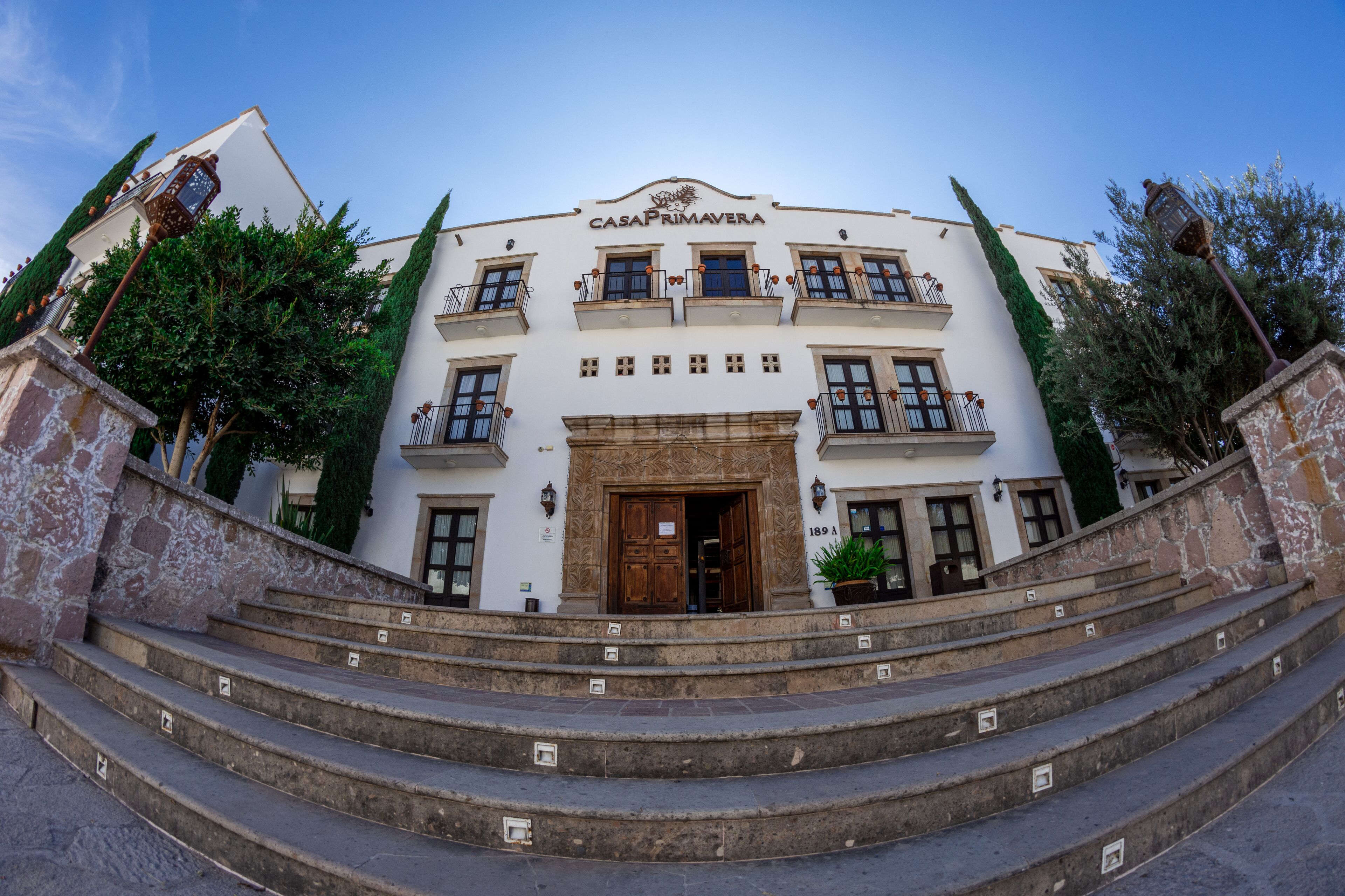 A building with a sign reading "CASA PRIMAVERA" at the top. It has multiple windows and balconies, and there are steps leading up to the entrance.