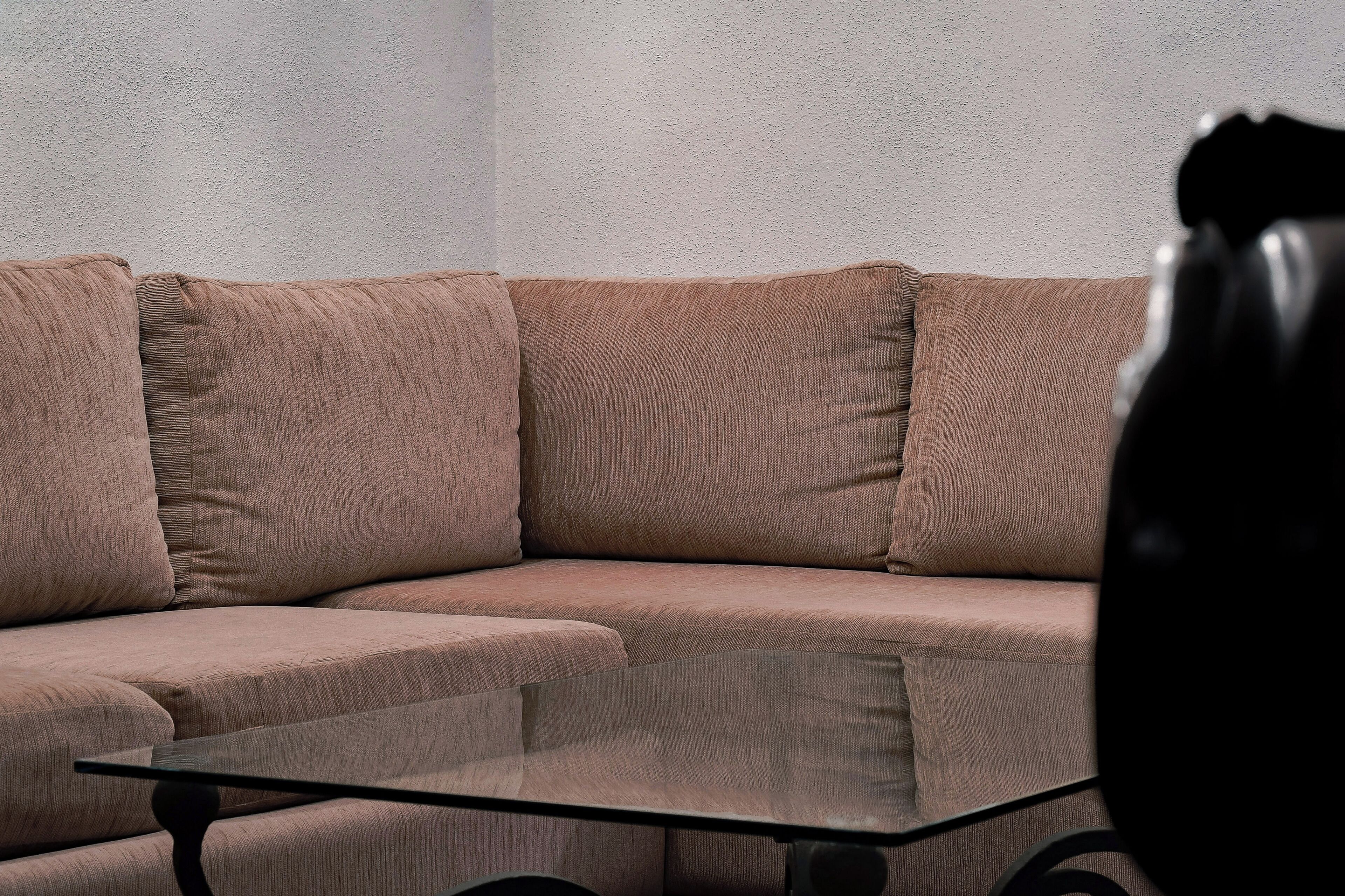 A corner of a room with a beige sectional sofa and a glass coffee table.