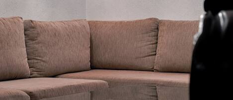 A corner of a room with a beige sectional sofa and a glass coffee table.