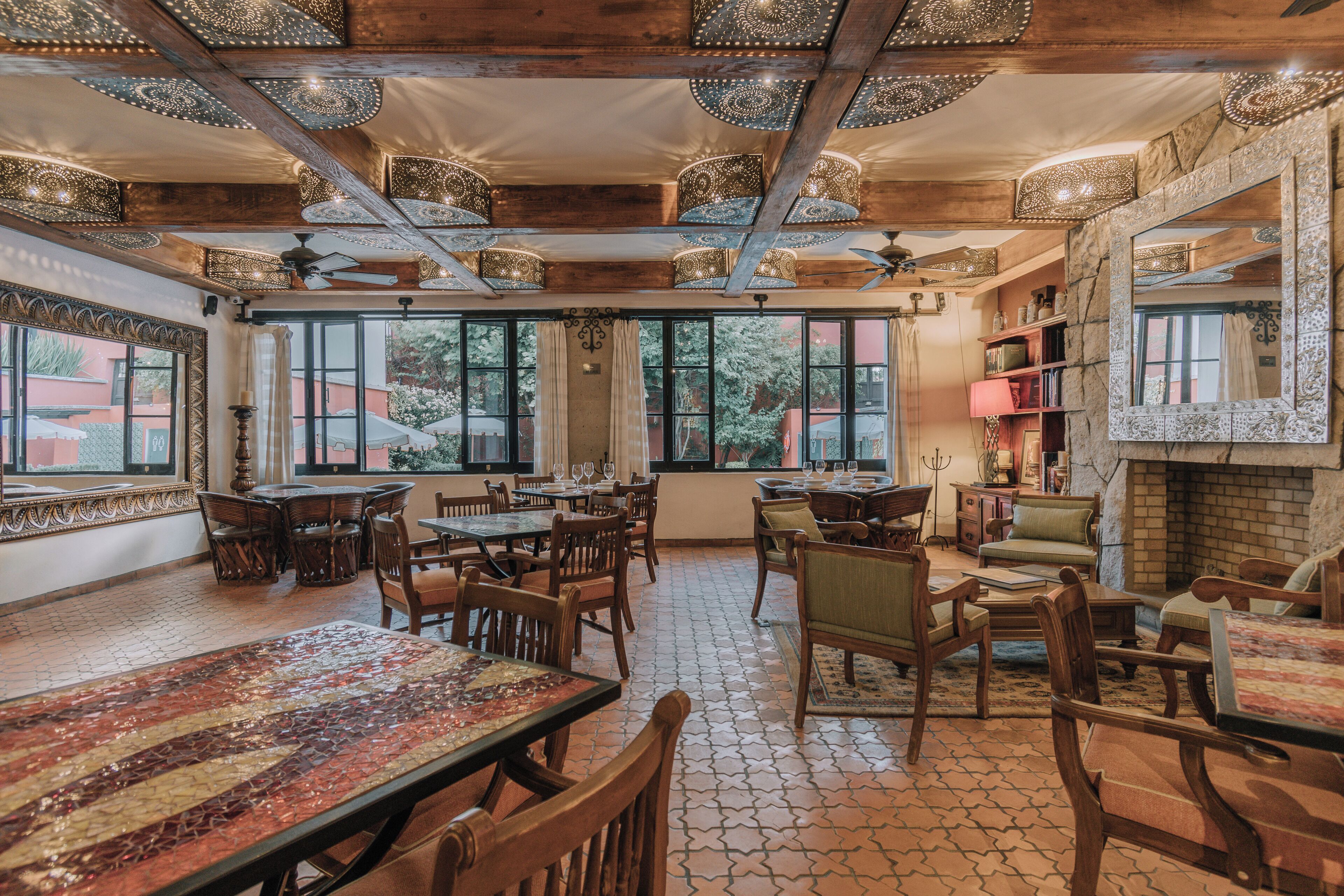 A spacious dining area with wooden tables and chairs, large windows, and a fireplace.