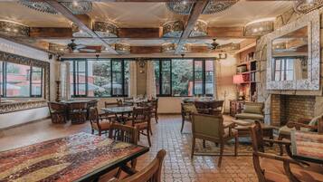 A spacious dining area with wooden tables and chairs, large windows, and a fireplace.