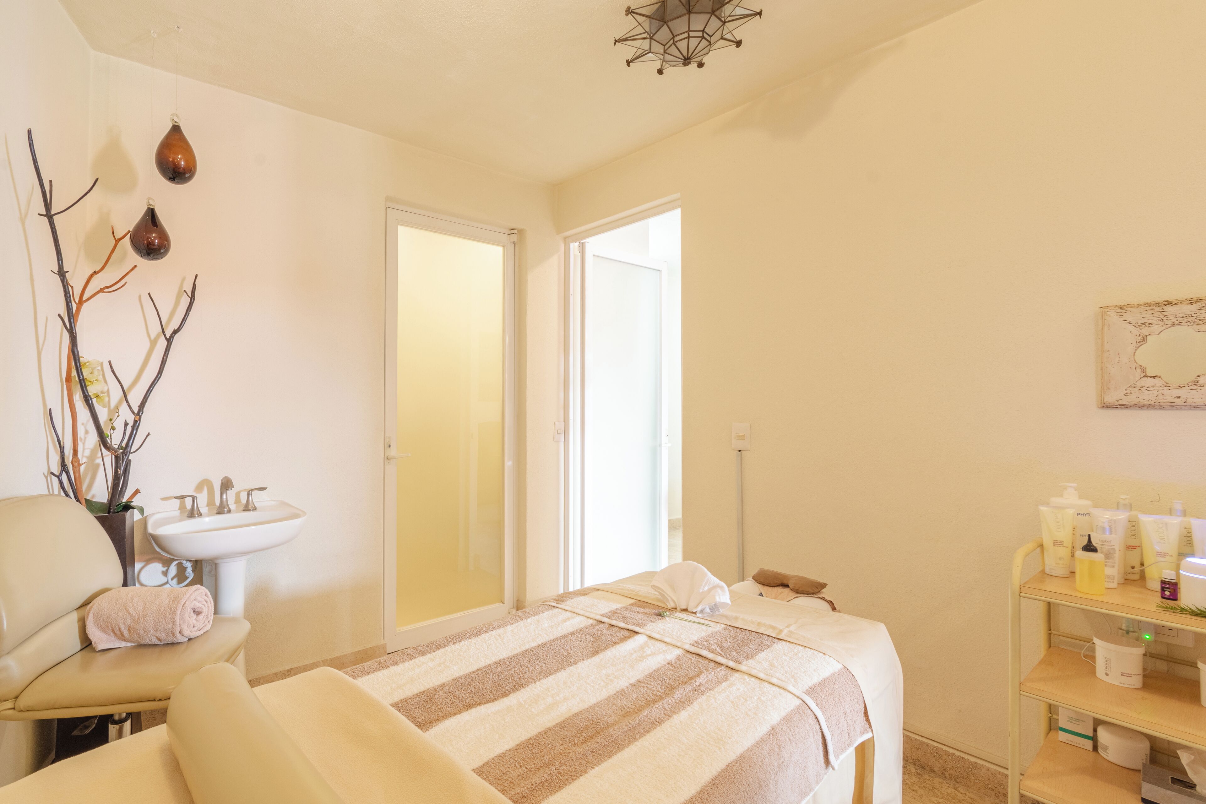 Een kamer met een bed, een stoel, een wastafel en een plank met toiletartikelen.