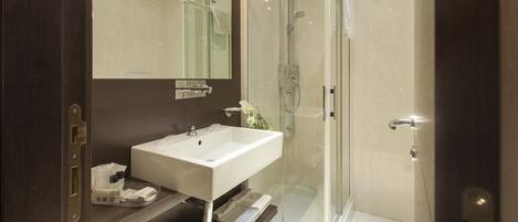 A modern bathroom with a glass-enclosed shower, a white sink, and a large mirror.
