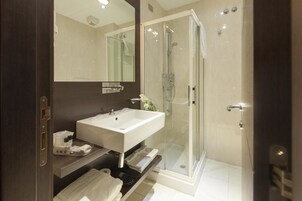 A modern bathroom with a glass-enclosed shower, a white sink, and a large mirror.