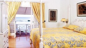 Ein Schlafzimmer mit Bett, Schreibtisch und Blick auf den Strand.