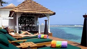 Eine Strandlounge mit Holzliegen und einem Gazebo mit Reetdach.